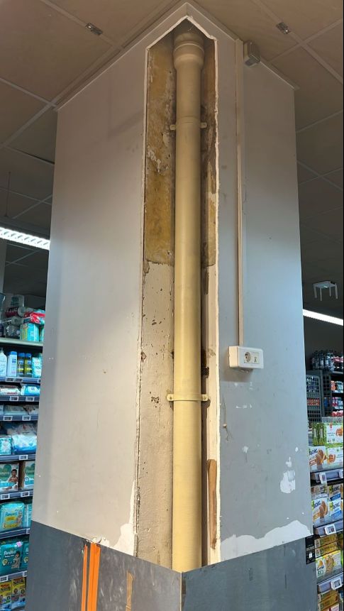 Poteau de magasin avec coffrage ouvert et descente PVC visible